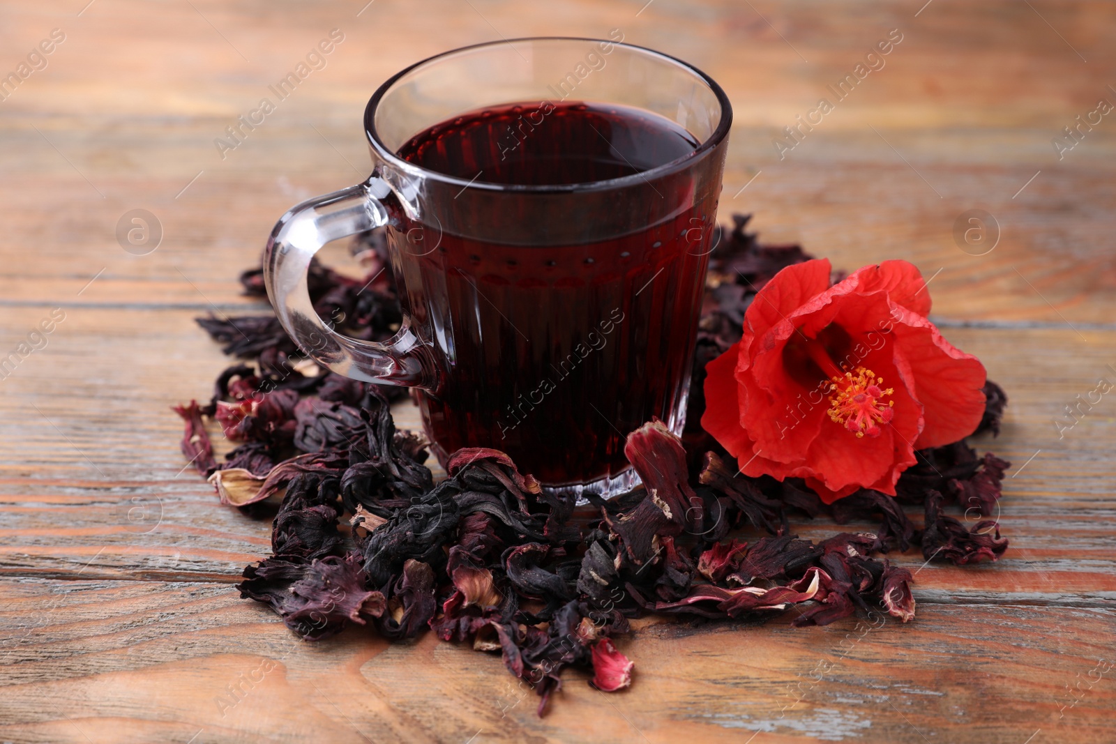 Delicious hibiscus tea and dry flowers on wooden table Photo of Delicious hibiscus tea and dry flowers on wooden table