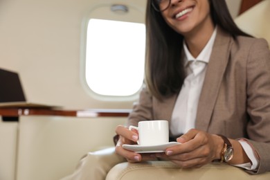 Businesswoman with cup of coffee in airplane during flight, closeup Photo of Businesswoman with cup of coffee in airplane during flight, closeup
