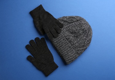 Photo of Woolen gloves and hat on blue background, flat lay