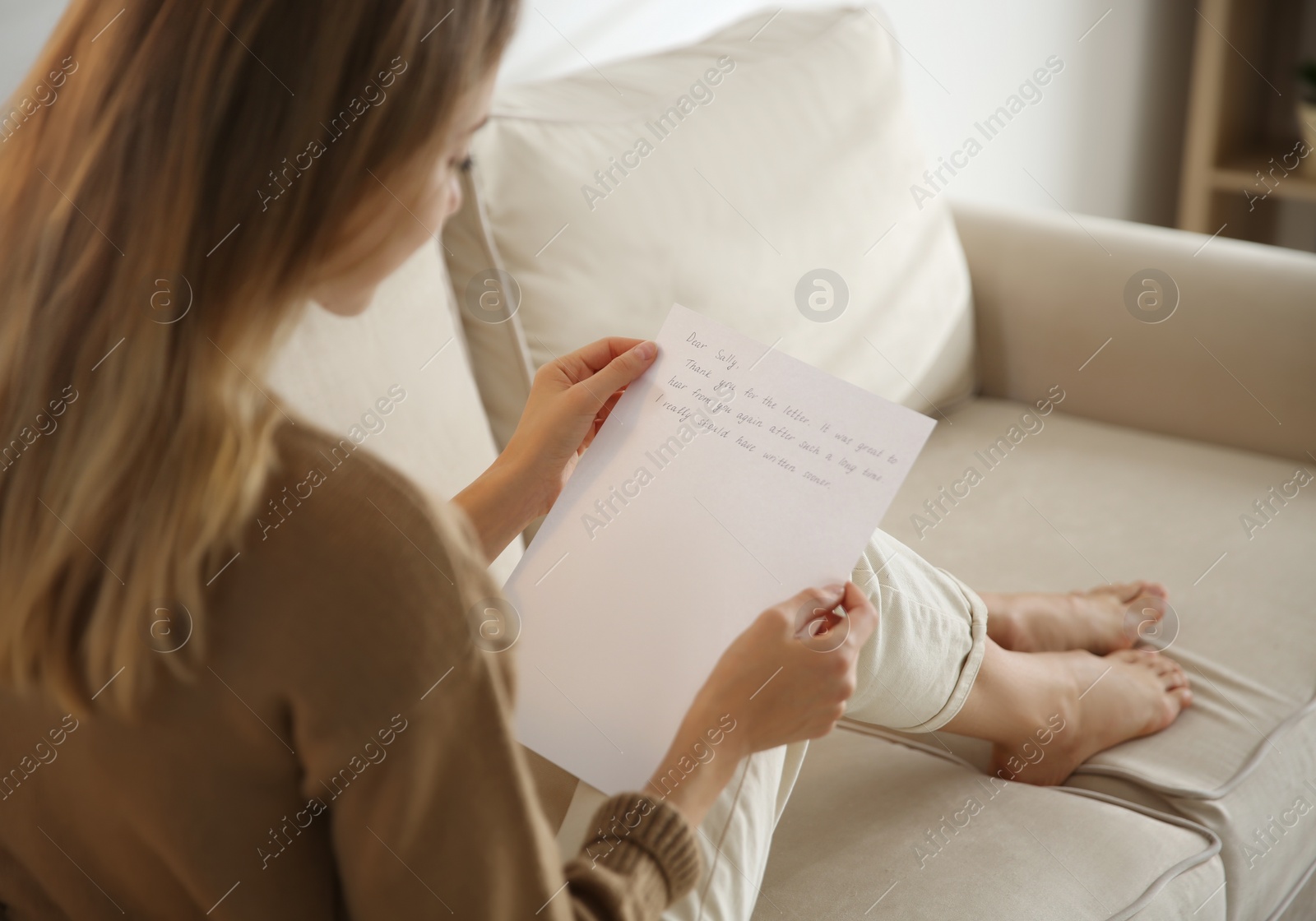 Woman reading letter on sofa at home, closeup Photo of Woman reading letter on sofa at home, closeup