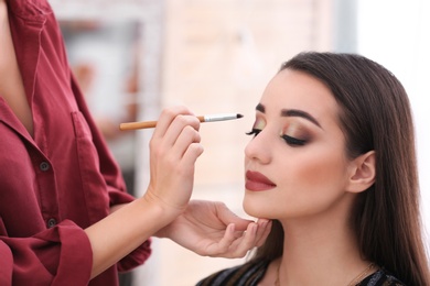 Professional visage artist applying makeup on woman's face in salon Photo of Professional visage artist applying makeup on woman's face in salon