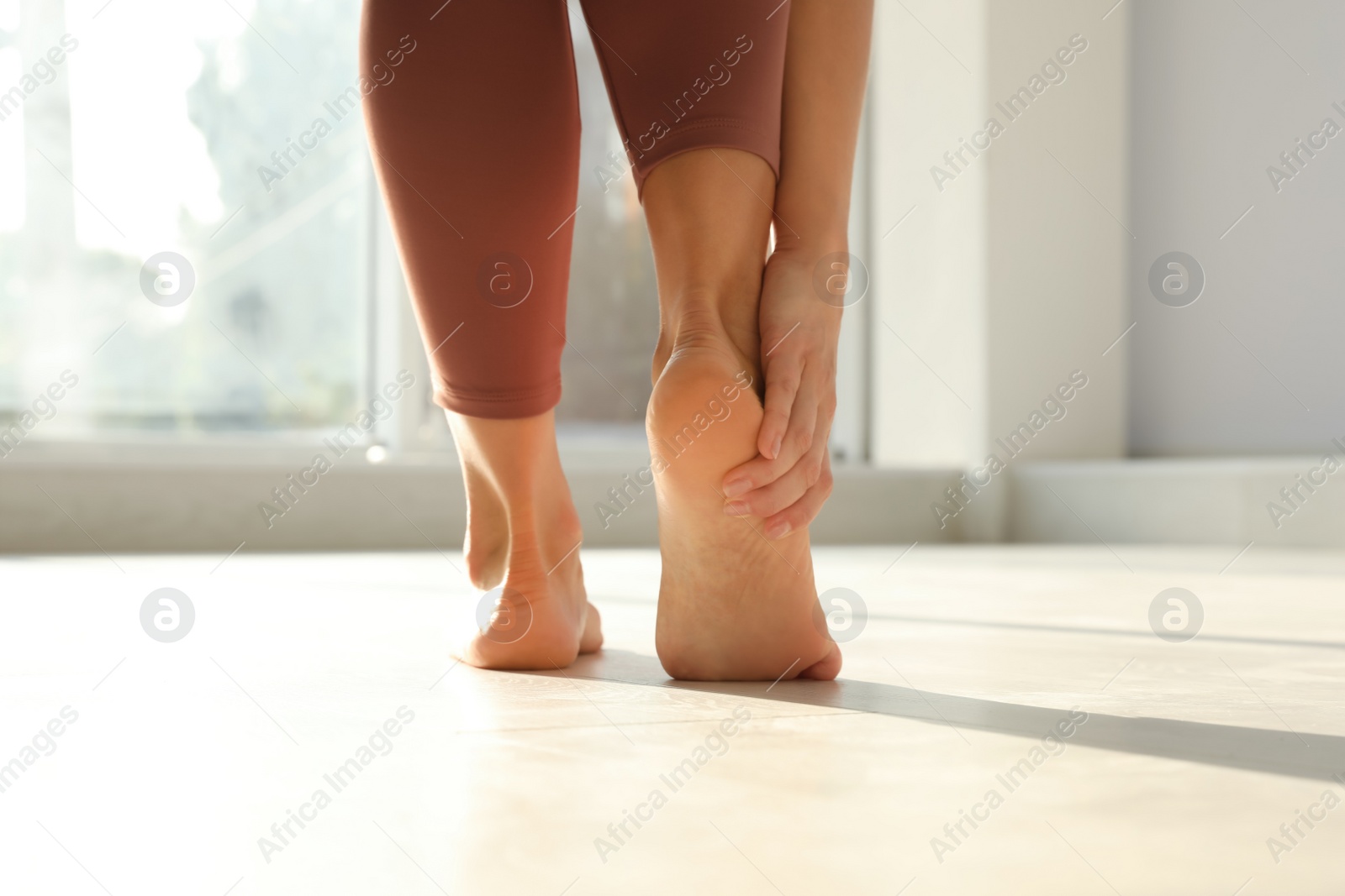 Back view of woman suffering from foot pain indoors, closeup Photo of Back view of woman suffering from foot pain indoors, closeup