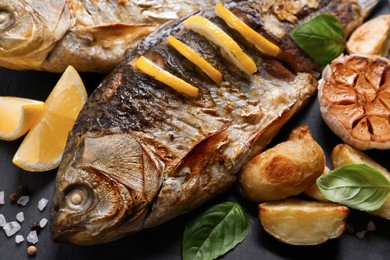 Tasty homemade roasted crucian carps served on slate plate, closeup. River fish Photo of Tasty homemade roasted crucian carps served on slate plate, closeup. River fish