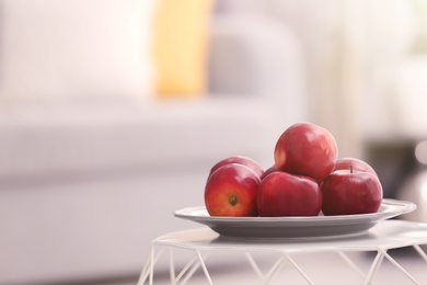 Plate with ripe red apples on table against blurred background Photo of Plate with ripe red apples on table against blurred background