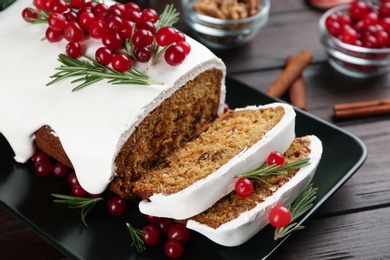 Traditional classic Christmas cake decorated with cranberries and rosemary on wooden table, closeup Photo of Traditional classic Christmas cake decorated with cranberries and rosemary on wooden table, closeup