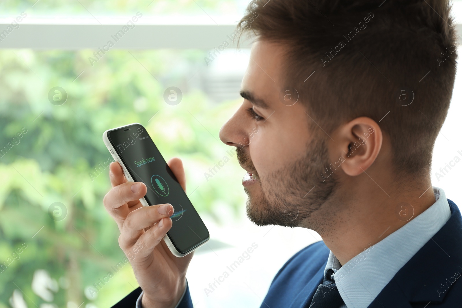 Young man using voice search on smartphone indoors Photo of Young man using voice search on smartphone indoors