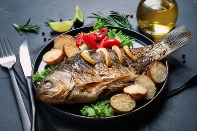 Tasty homemade roasted crucian carp served on black table. River fish Photo of Tasty homemade roasted crucian carp served on black table. River fish