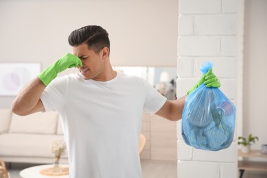Man holding full garbage bag at home Photo of Man holding full garbage bag at home