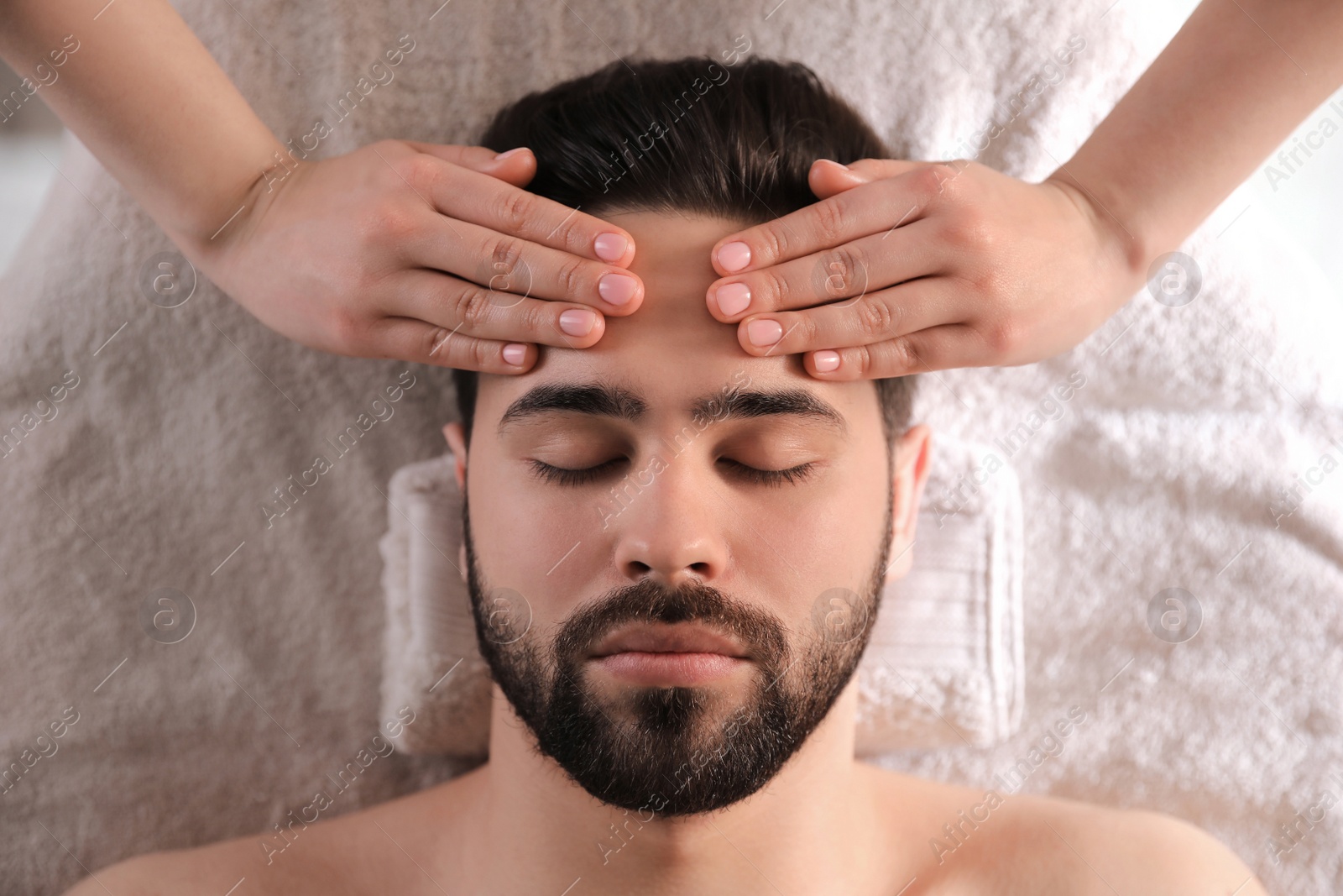 Young man receiving facial massage in beauty salon, top view Photo of Young man receiving facial massage in beauty salon, top view