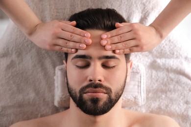 Young man receiving facial massage in beauty salon, top view Photo of Young man receiving facial massage in beauty salon, top view
