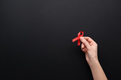 Woman holding red awareness ribbon on black background, top view with space for text. World AIDS disease day Photo of Woman holding red awareness ribbon on black background, top view with space for text. World AIDS disease day