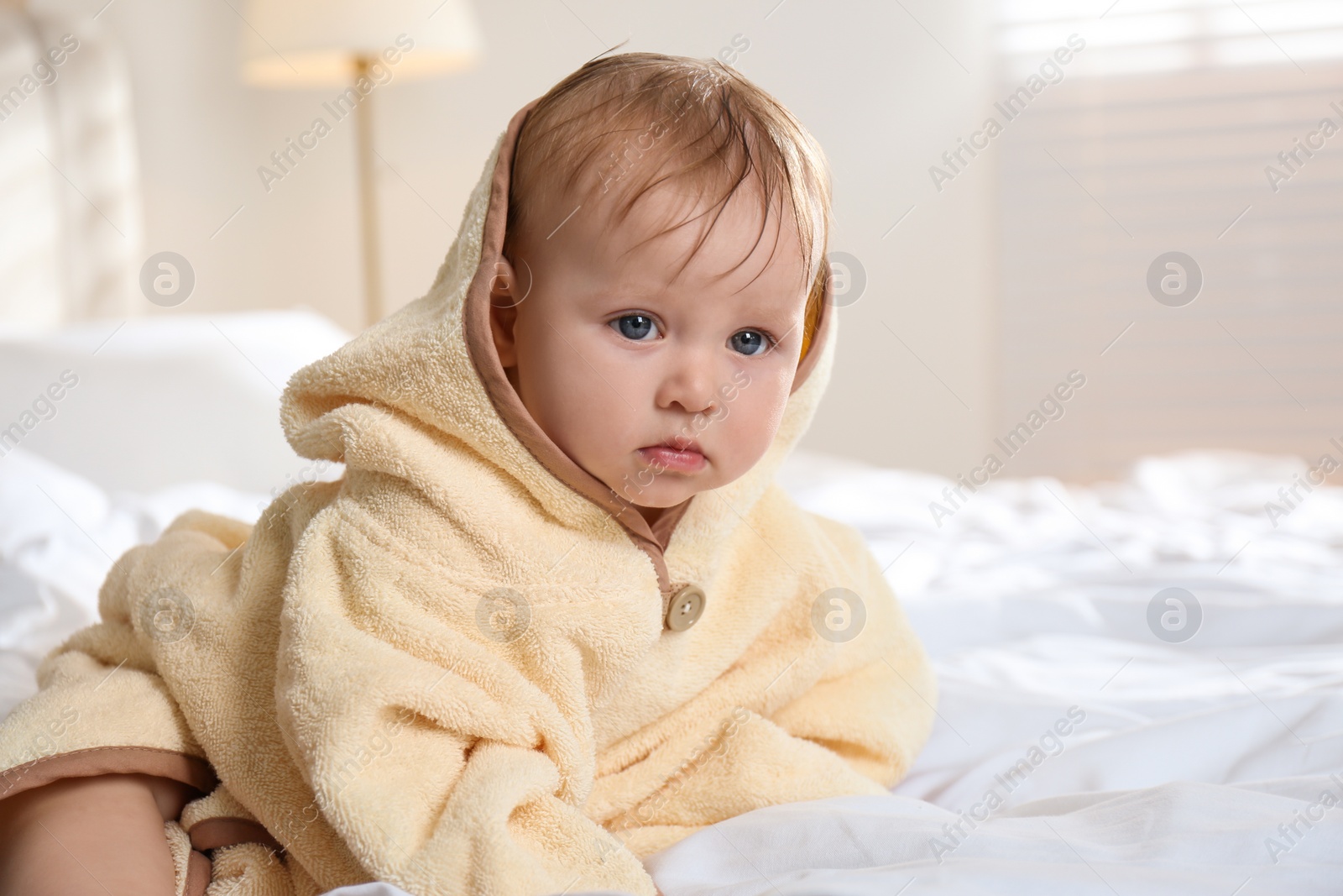 Cute little baby in yellow hooded towel on bed after bath Photo of Cute little baby in yellow hooded towel on bed after bath