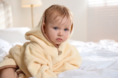 Cute little baby in yellow hooded towel on bed after bath Photo of Cute little baby in yellow hooded towel on bed after bath