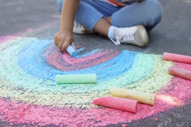 Little child drawing rainbow with colorful chalk on asphalt, closeup Photo of Little child drawing rainbow with colorful chalk on asphalt, closeup