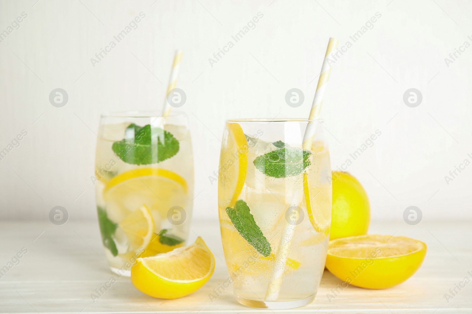 Cool freshly made lemonade and fruits on white wooden table Photo of Cool freshly made lemonade and fruits on white wooden table