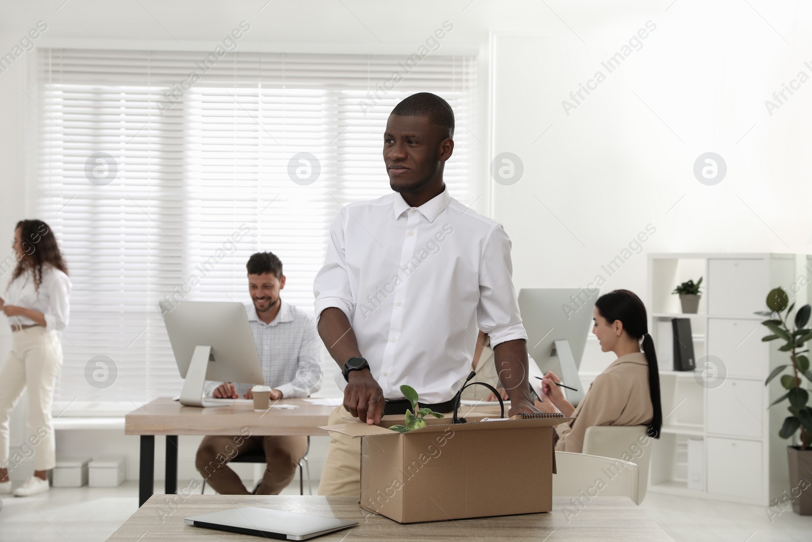 New coworker unpacking box with personal items at workplace in office Photo of New coworker unpacking box with personal items at workplace in office
