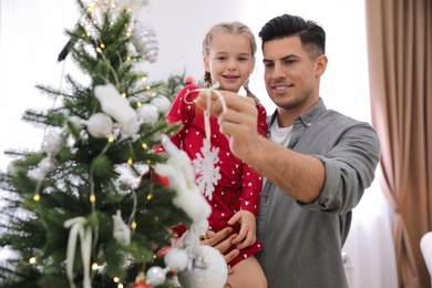 Happy father with his cute daughter decorating Christmas tree together at home Photo of Happy father with his cute daughter decorating Christmas tree together at home