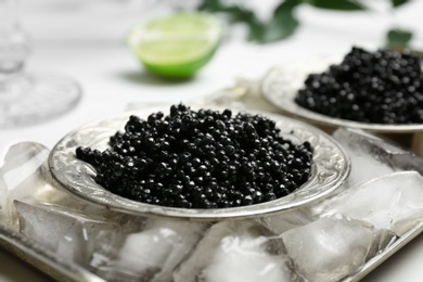 Plate with black caviar served with ice cubes on metal tray Photo of Plate with black caviar served with ice cubes on metal tray
