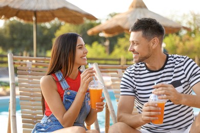 Happy couple with cups of refreshing drink resting in deck chairs Image of Happy couple with cups of refreshing drink resting in deck chairs