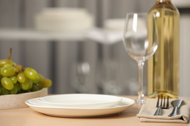 White plates, glass, cutlery and wine served for dinner on wooden table Photo of White plates, glass, cutlery and wine served for dinner on wooden table