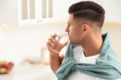 Man drinking pure water from glass in kitchen. Space for text Photo of Man drinking pure water from glass in kitchen. Space for text