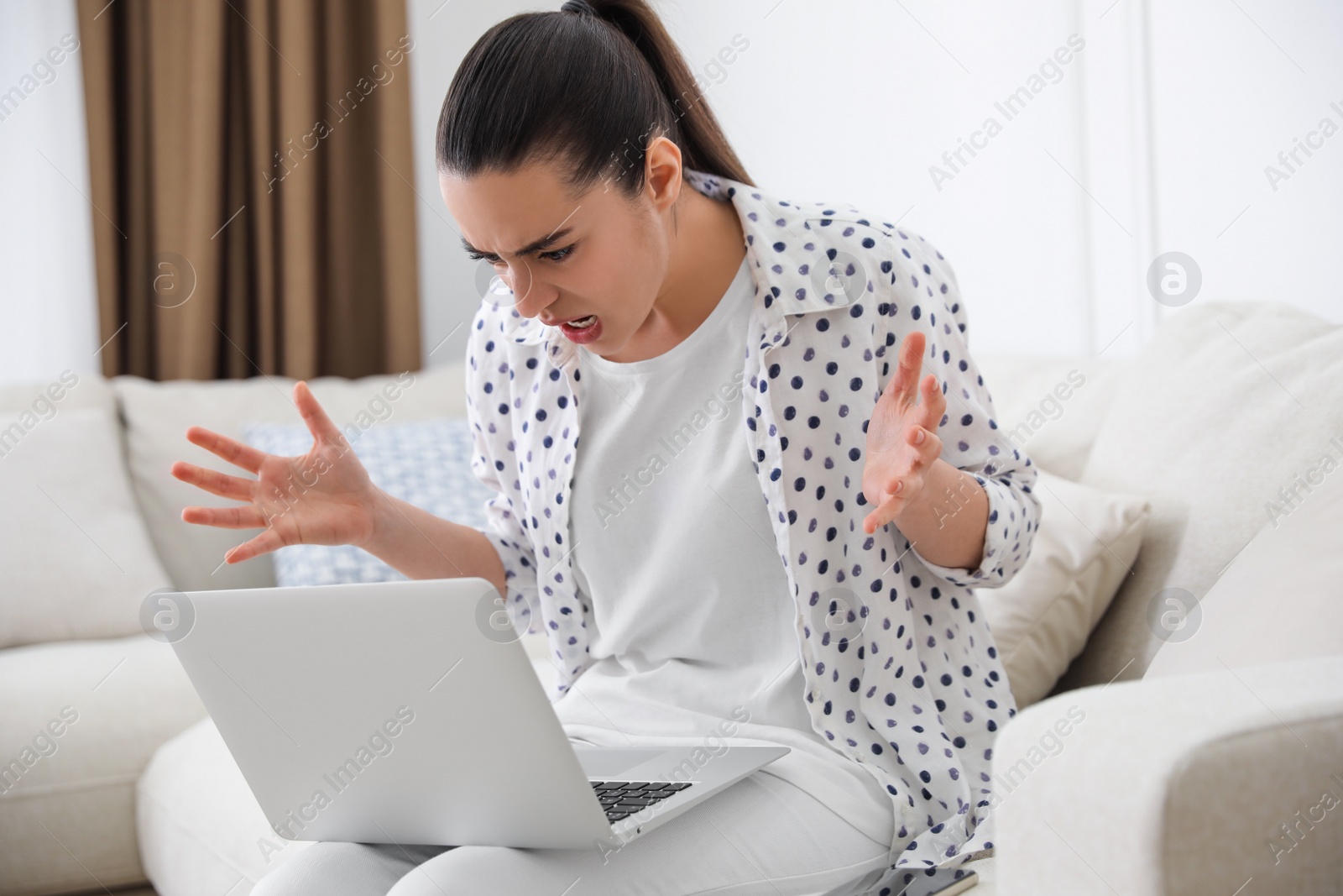 Emotional young woman with laptop at home. Online hate concept Photo of Emotional young woman with laptop at home. Online hate concept