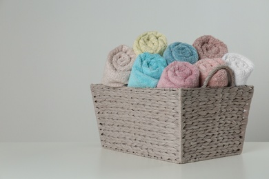 Wicker basket with clean soft towels on light background. Space for text Photo of Wicker basket with clean soft towels on light background. Space for text