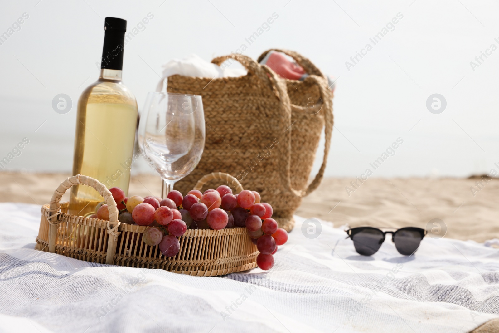 Bag, blanket, wine and other stuff for beach picnic on sandy seashore Photo of Bag, blanket, wine and other stuff for beach picnic on sandy seashore