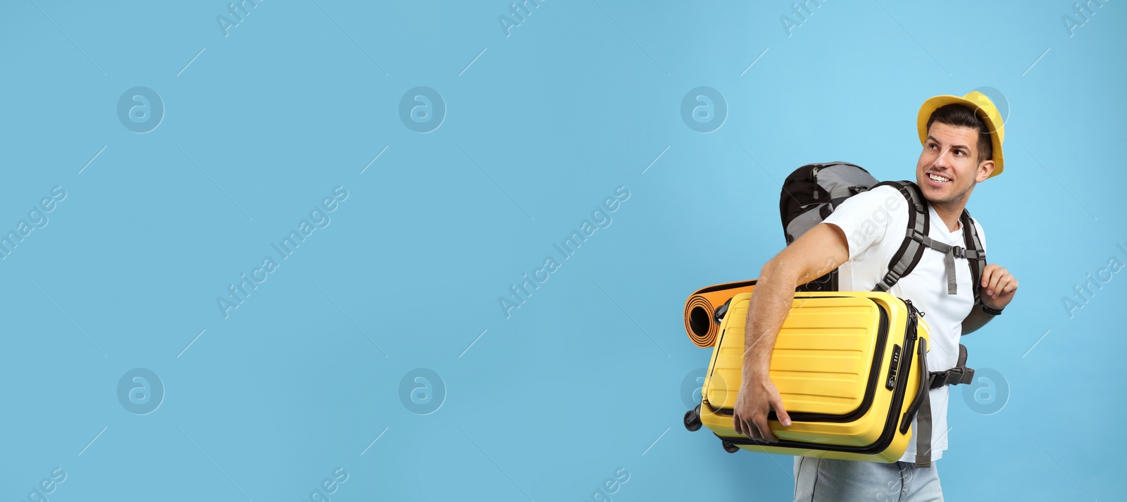 Male tourist with travel backpack and suitcase on turquoise background, space for text Photo of Male tourist with travel backpack and suitcase on turquoise background, space for text