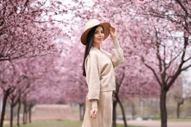 Pretty young woman in park with blooming trees. Spring look Photo of Pretty young woman in park with blooming trees. Spring look