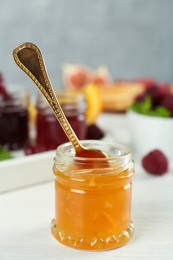 Open glass jar of sweet jam with spoon on white wooden table Photo of Open glass jar of sweet jam with spoon on white wooden table