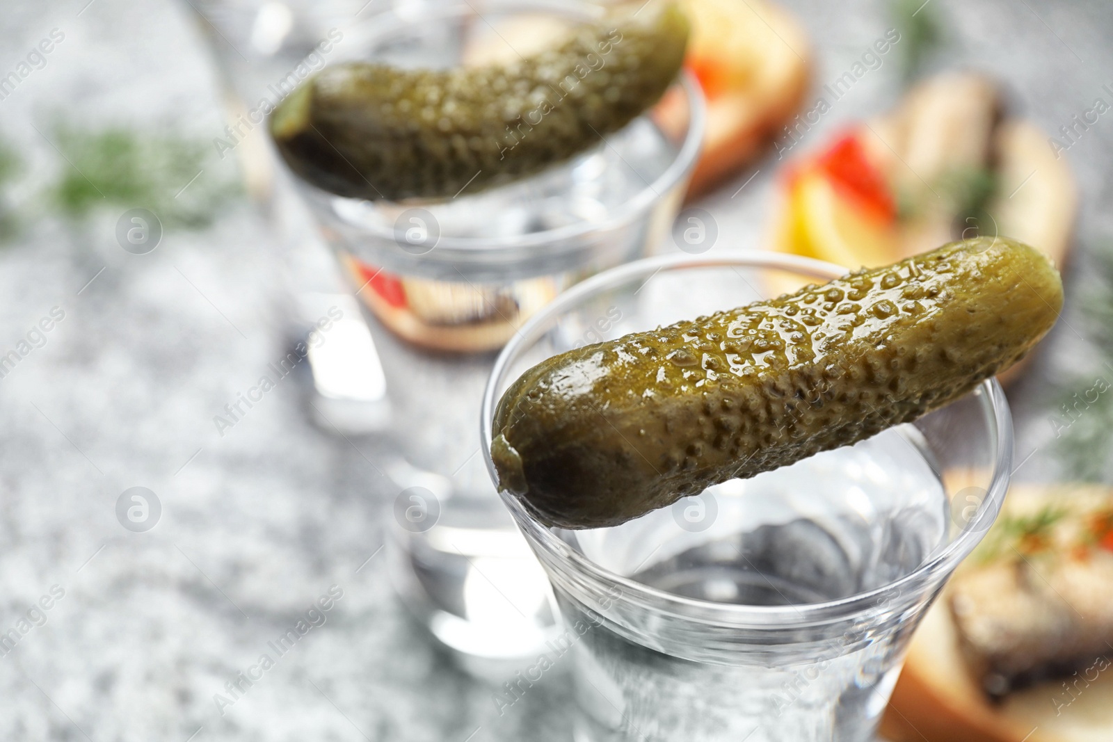 Cold Russian vodka with pickles on grey table, closeup Photo of Cold Russian vodka with pickles on grey table, closeup