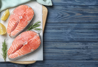 Top view of fresh raw salmon with lemon and rosemary on blue wooden table, space for text. Fish delicacy Photo of Top view of fresh raw salmon with lemon and rosemary on blue wooden table, space for text. Fish delicacy