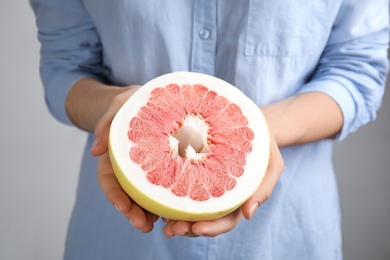 Woman holding half of red pomelo on light background, closeup Photo of Woman holding half of red pomelo on light background, closeup