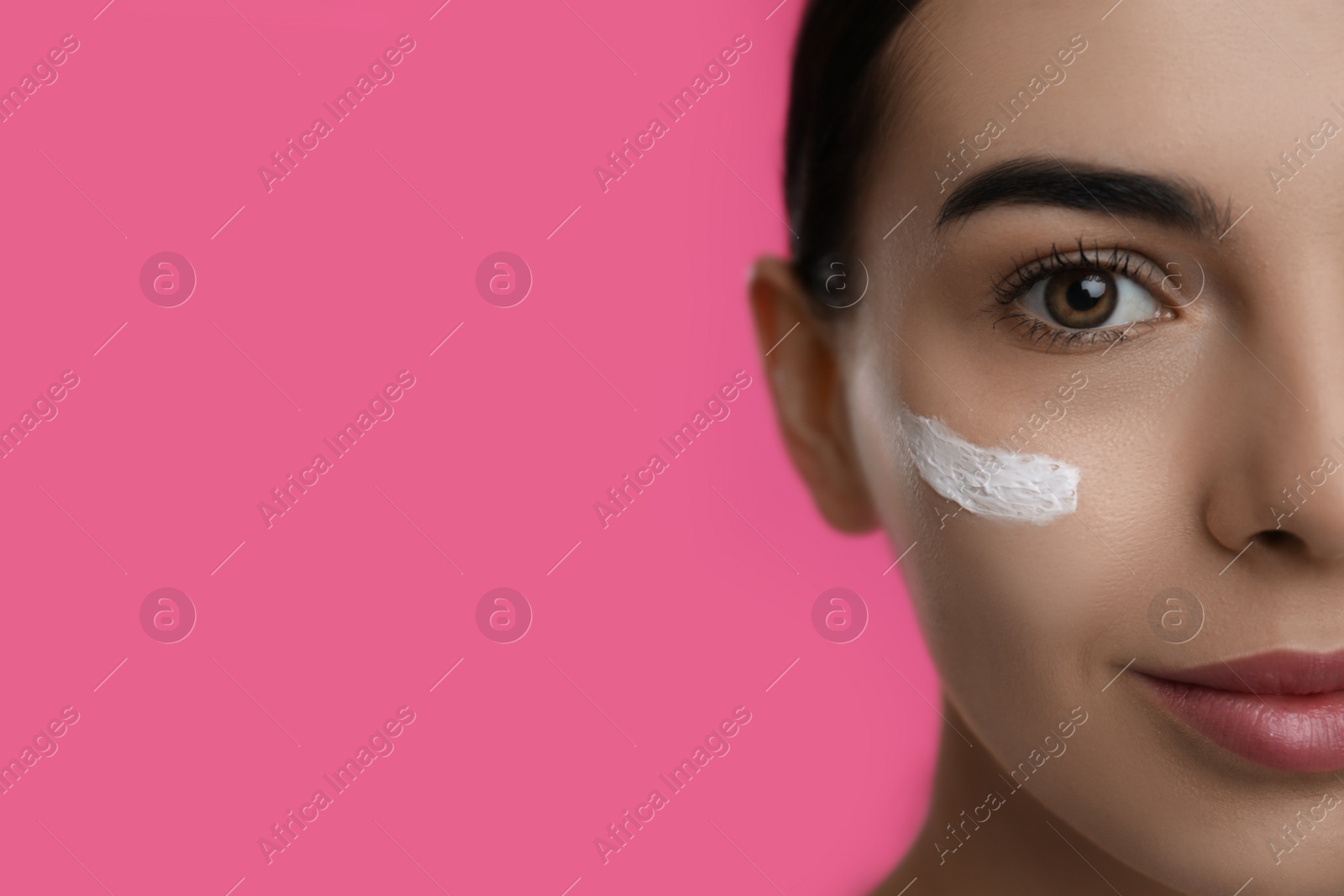 Young woman with cream on face against pink background, closeup. Space for text Photo of Young woman with cream on face against pink background, closeup. Space for text