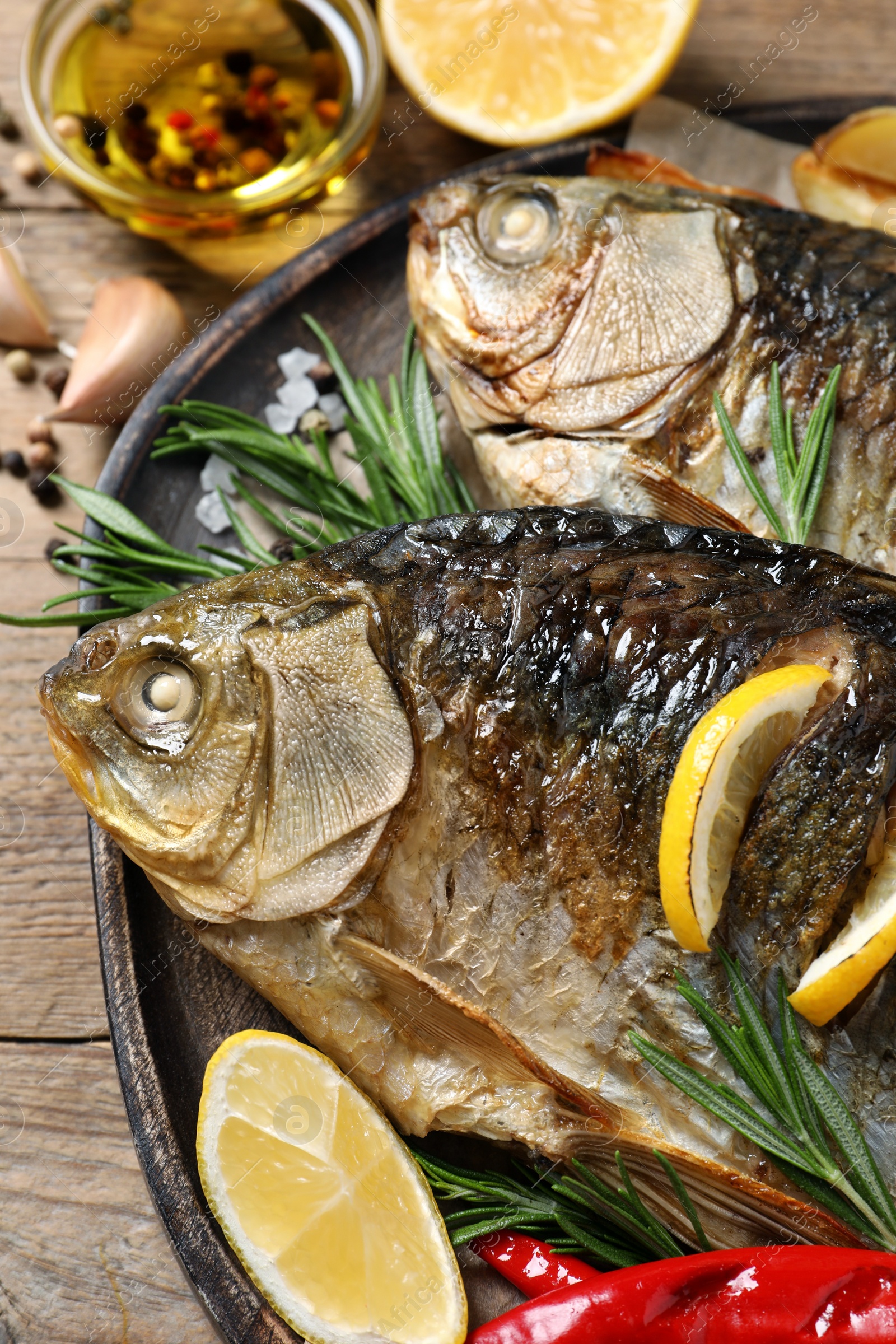 Photo of Tasty homemade roasted crucian carps served on wooden table, closeup. River fish