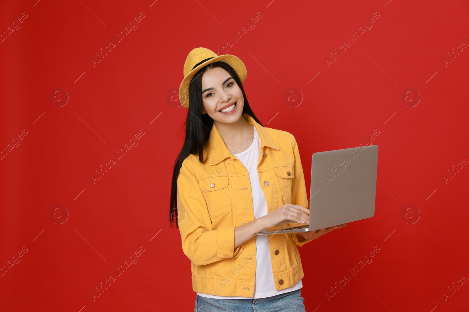 Young woman with modern laptop on red background Photo of Young woman with modern laptop on red background