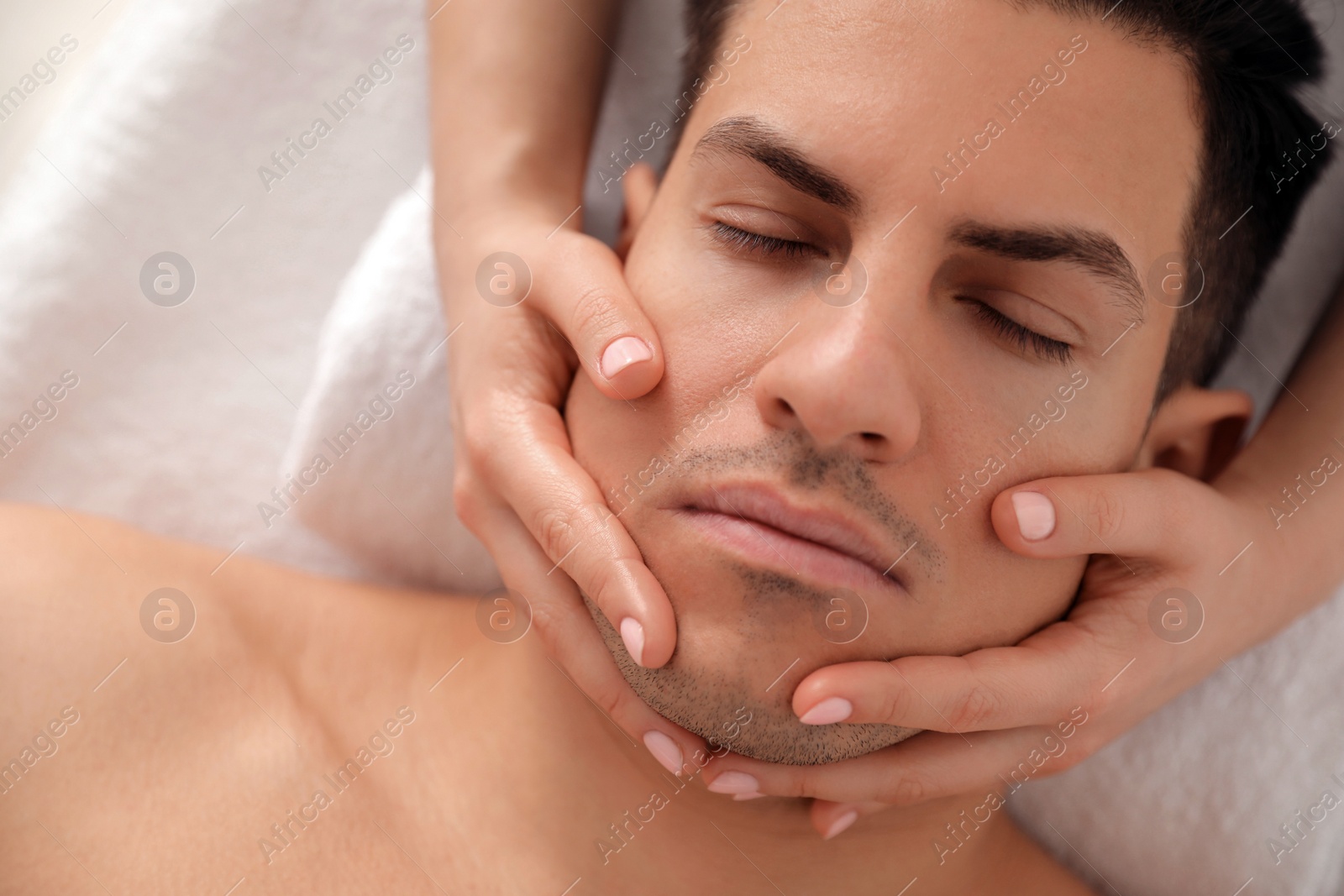 Man receiving facial massage in beauty salon, top view Photo of Man receiving facial massage in beauty salon, top view