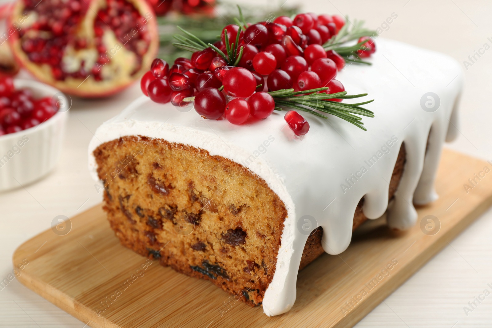 Traditional classic Christmas cake decorated with cranberries, pomegranate seeds and rosemary on white table, closeup Photo of Traditional classic Christmas cake decorated with cranberries, pomegranate seeds and rosemary on white table, closeup