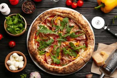 Tasty pizza with meat and arugula on black wooden table, flat lay Photo of Tasty pizza with meat and arugula on black wooden table, flat lay