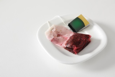 Saucer with used tea bag on white table Photo of Saucer with used tea bag on white table