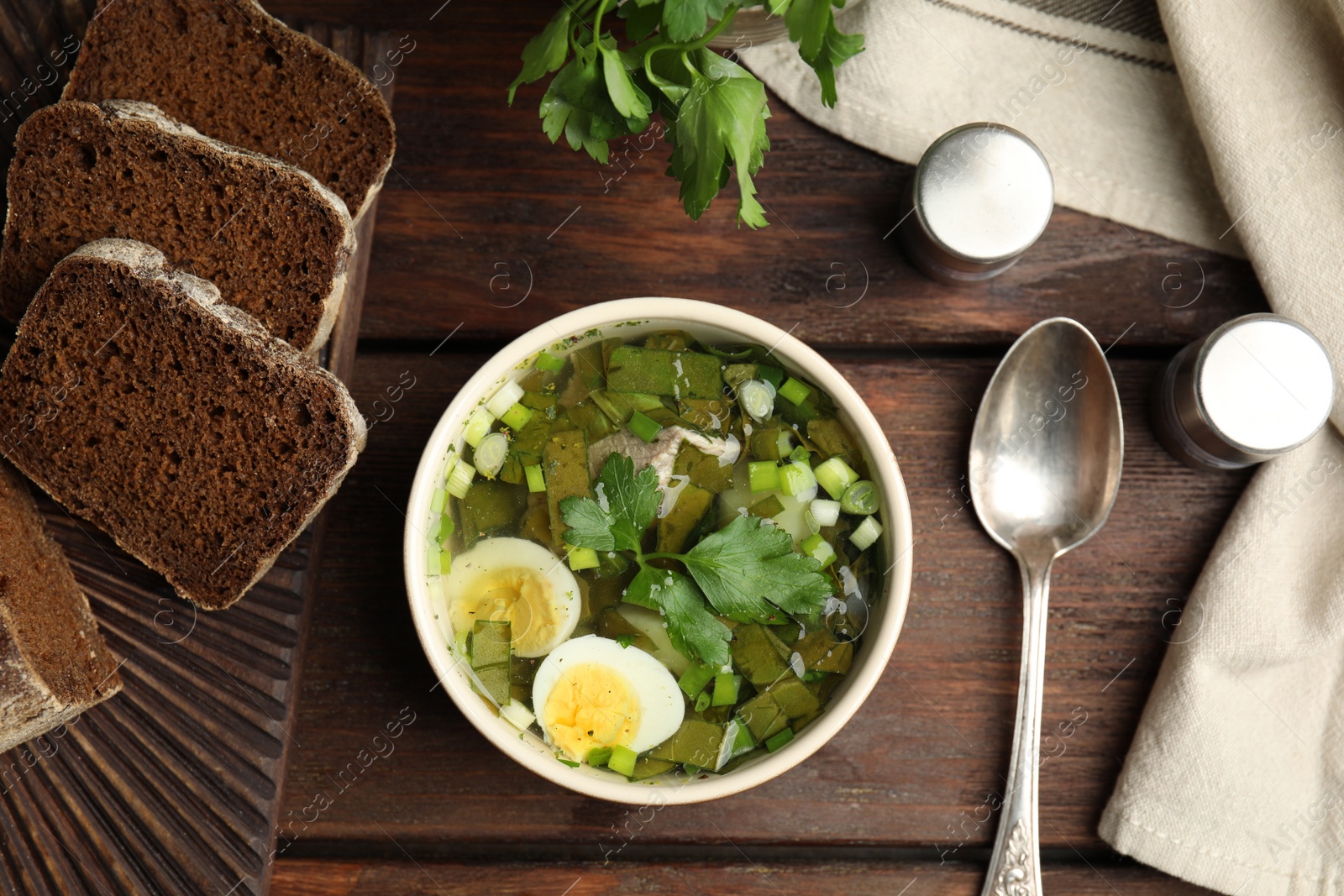 Delicious sorrel soup with eggs served on wooden table, flat lay Photo of Delicious sorrel soup with eggs served on wooden table, flat lay