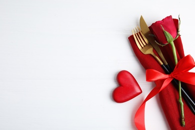 Top view of cutlery with napkin and decorative heart on white wooden table, space for text. Valentine's Day romantic dinner Photo of Top view of cutlery with napkin and decorative heart on white wooden table, space for text. Valentine's Day romantic dinner