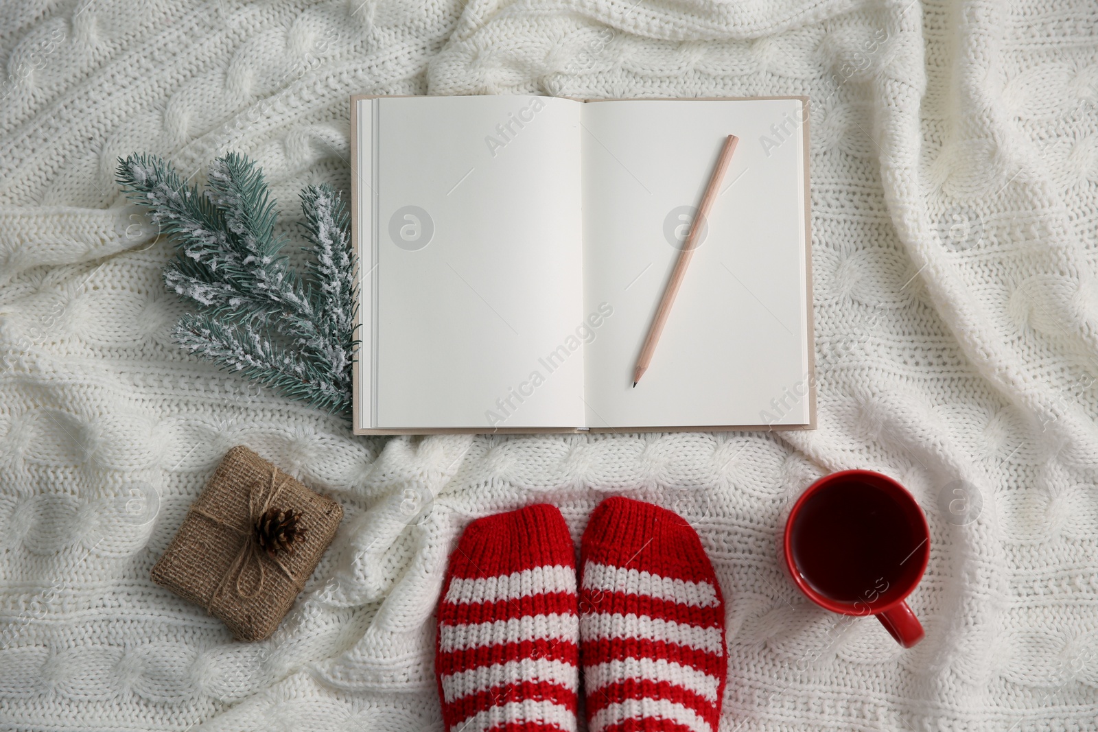 Woman with cup of hot winter drink and notebook on knitted plaid, top view. Cozy season Photo of Woman with cup of hot winter drink and notebook on knitted plaid, top view. Cozy season