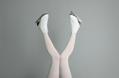 Woman in elegant white ice skates on grey background, closeup of legs Photo of Woman in elegant white ice skates on grey background, closeup of legs