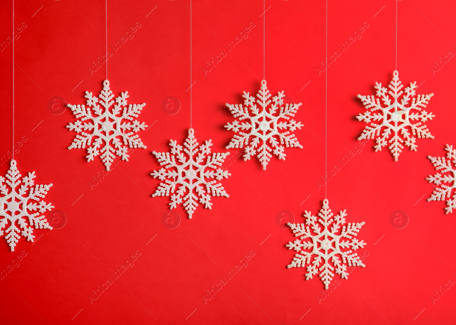 Beautiful decorative snowflakes hanging on red background Photo of Beautiful decorative snowflakes hanging on red background