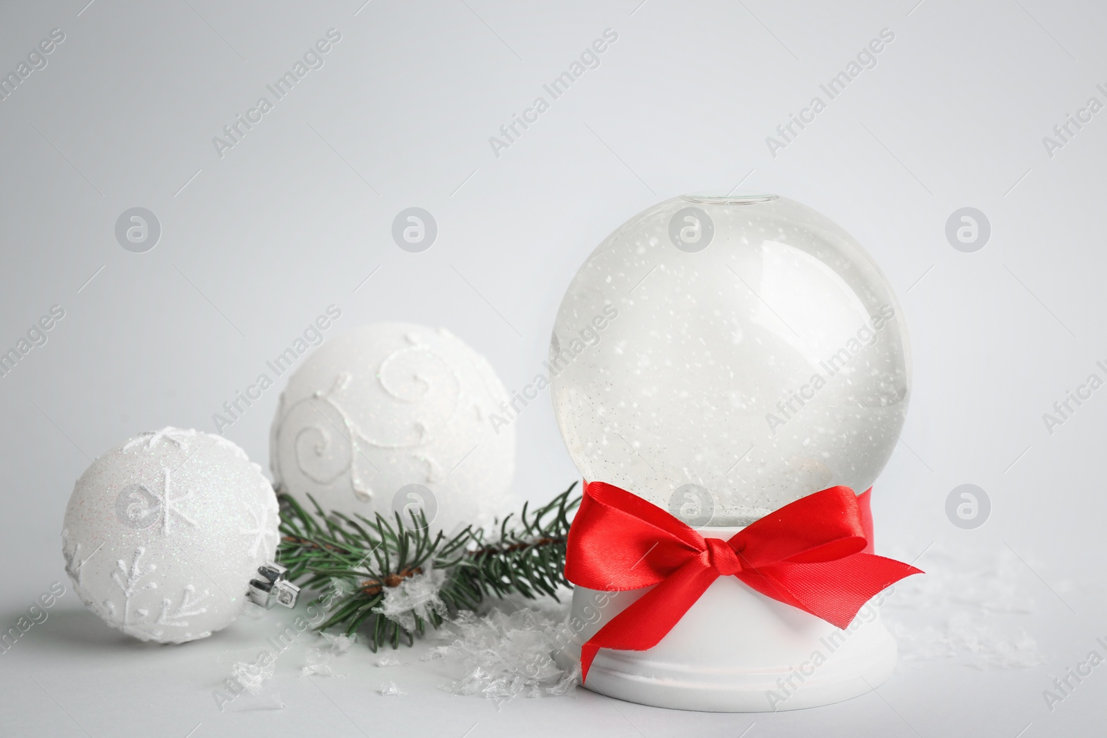 Beautiful empty snow globe, Christmas balls and fir branches on light grey background Photo of Beautiful empty snow globe, Christmas balls and fir branches on light grey background
