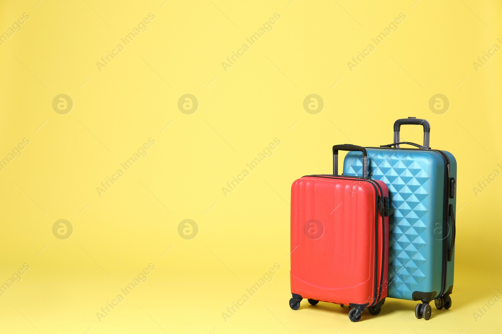 Stylish suitcases on yellow background. Space for text Photo of Stylish suitcases on yellow background. Space for text