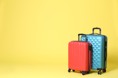 Photo of Stylish suitcases on yellow background. Space for text
