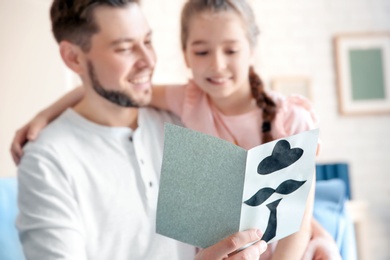 Photo of Little girl greeting her dad with Father's Day at home